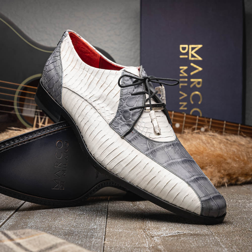 The Marco Di Milano Moncalieri Gray / White men's dress shoes feature a luxury white and grey crocodile pattern, black laces, and black soles, with one shoe stylishly propped against the other.