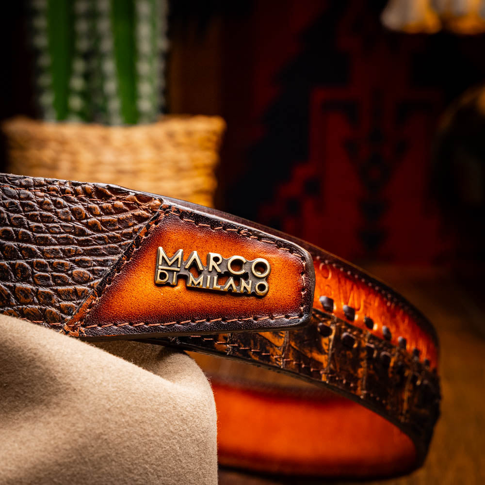 The Montana Belt Aged Brown by Marco Di Milano features aged brown leather with embossed patterns, metal studs, a bold gold MD monogram buckle, and the brand name on the strap for a sophisticated Western look.