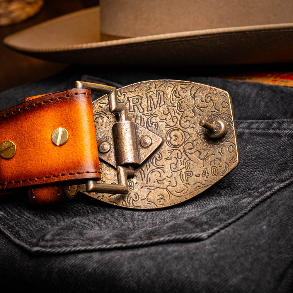 The Montana Belt Aged Brown by Marco Di Milano features aged brown leather with embossed patterns, metal studs, a bold gold MD monogram buckle, and the brand name on the strap for a sophisticated Western look.