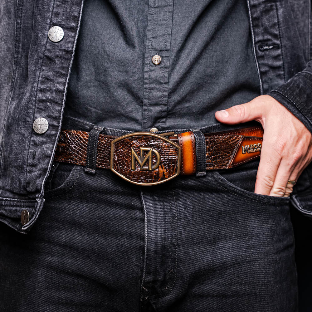 The Montana Belt Aged Brown by Marco Di Milano features aged brown leather with embossed patterns, metal studs, a bold gold MD monogram buckle, and the brand name on the strap for a sophisticated Western look.