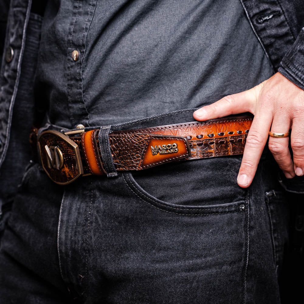 The Montana Belt Aged Brown by Marco Di Milano features aged brown leather with embossed patterns, metal studs, a bold gold MD monogram buckle, and the brand name on the strap for a sophisticated Western look.