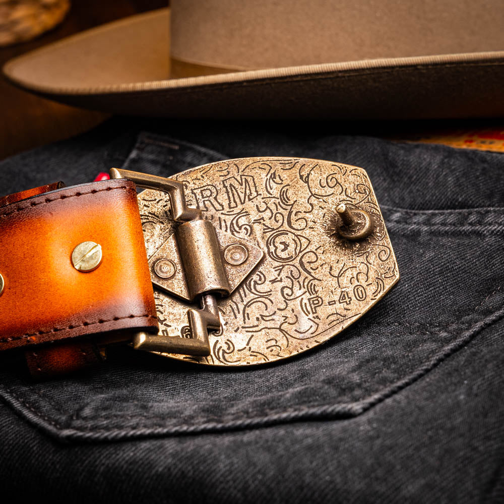 The Montana Belt Aged Maple by Marco Di Milano, featuring stitched details and a large gold MD monogram buckle with embossed branding, is coiled against a white background.