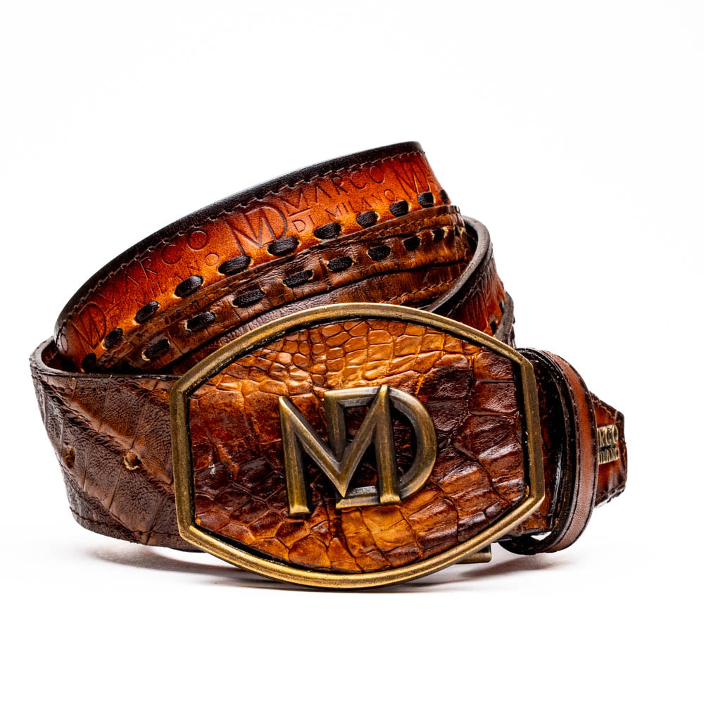 The Montana Belt Aged Maple by Marco Di Milano, featuring stitched details and a large gold MD monogram buckle with embossed branding, is coiled against a white background.