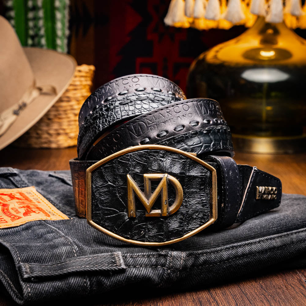 The Marco Di Milano Montana Belt Black features handcrafted black textured leather and a large gold MD monogram buckle, elegantly coiled against a white background.