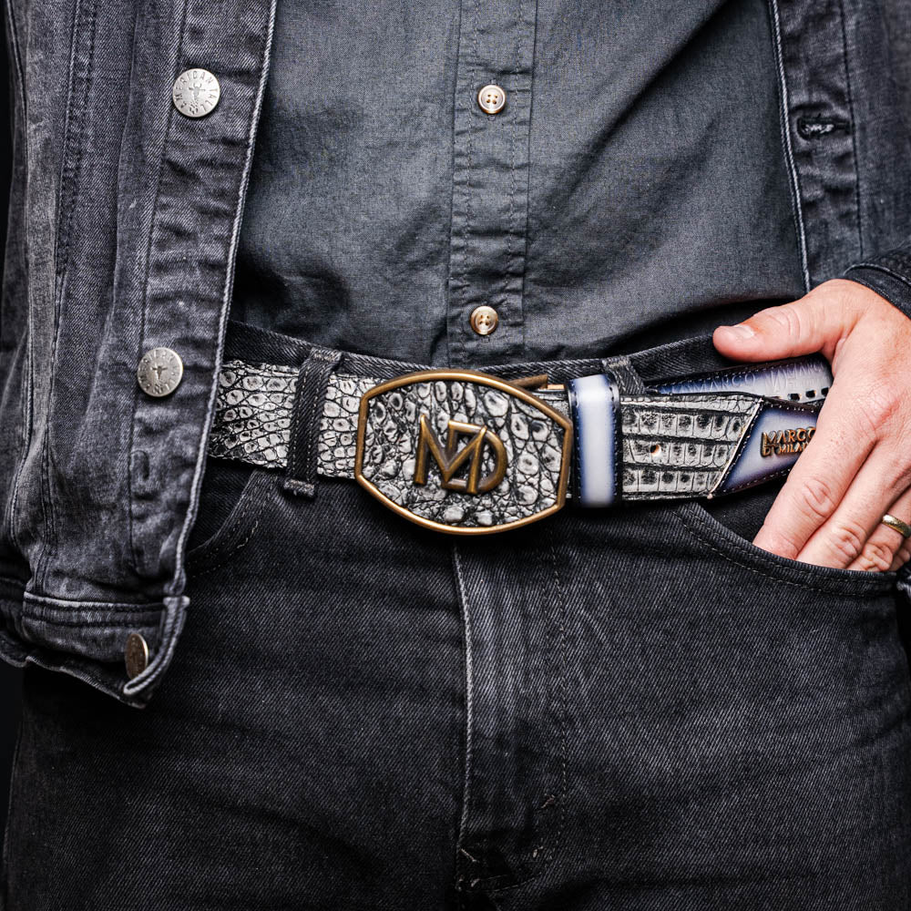 The Montana Belt Stone Gray by Marco Di Milano is a handcrafted leather belt, featuring a gold MD logo buckle and embossed branding on the caiman crocodile strap.