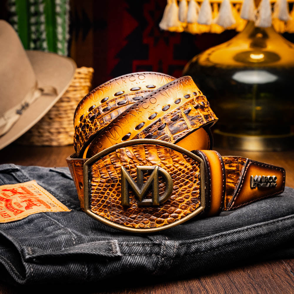 The Montana Belt Mustard Brown by Marco Di Milano features a brown caiman crocodile texture, a bold gold "MD" buckle, and "MARCO DI MILANO" embossed on the side, reflecting the brand’s renowned craftsmanship.