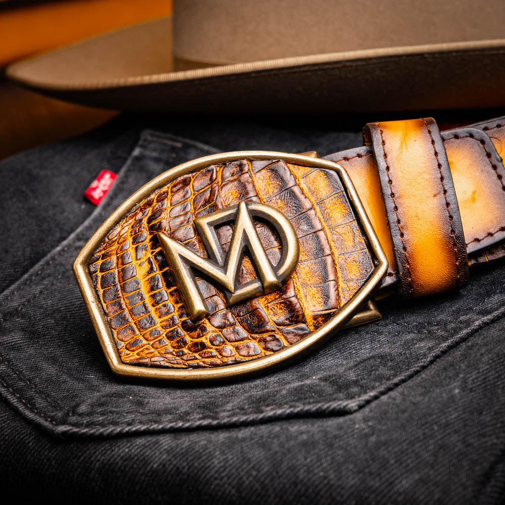 The Montana Belt Mustard Brown by Marco Di Milano features a brown caiman crocodile texture, a bold gold "MD" buckle, and "MARCO DI MILANO" embossed on the side, reflecting the brand’s renowned craftsmanship.