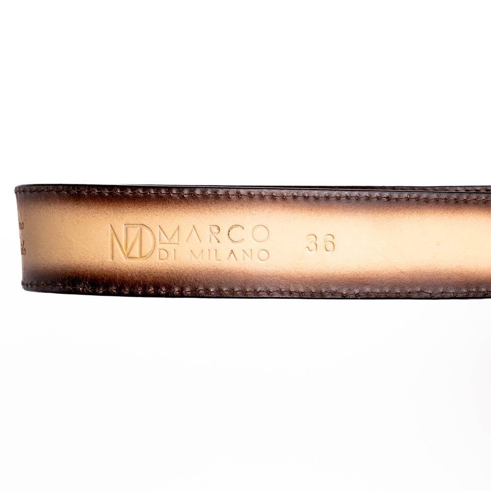 The Montana Belt Stone Orix by Marco Di Milano is a brown handcrafted leather belt with a caiman crocodile pattern and a bold gold MD monogram buckle, elegantly coiled on a white background.