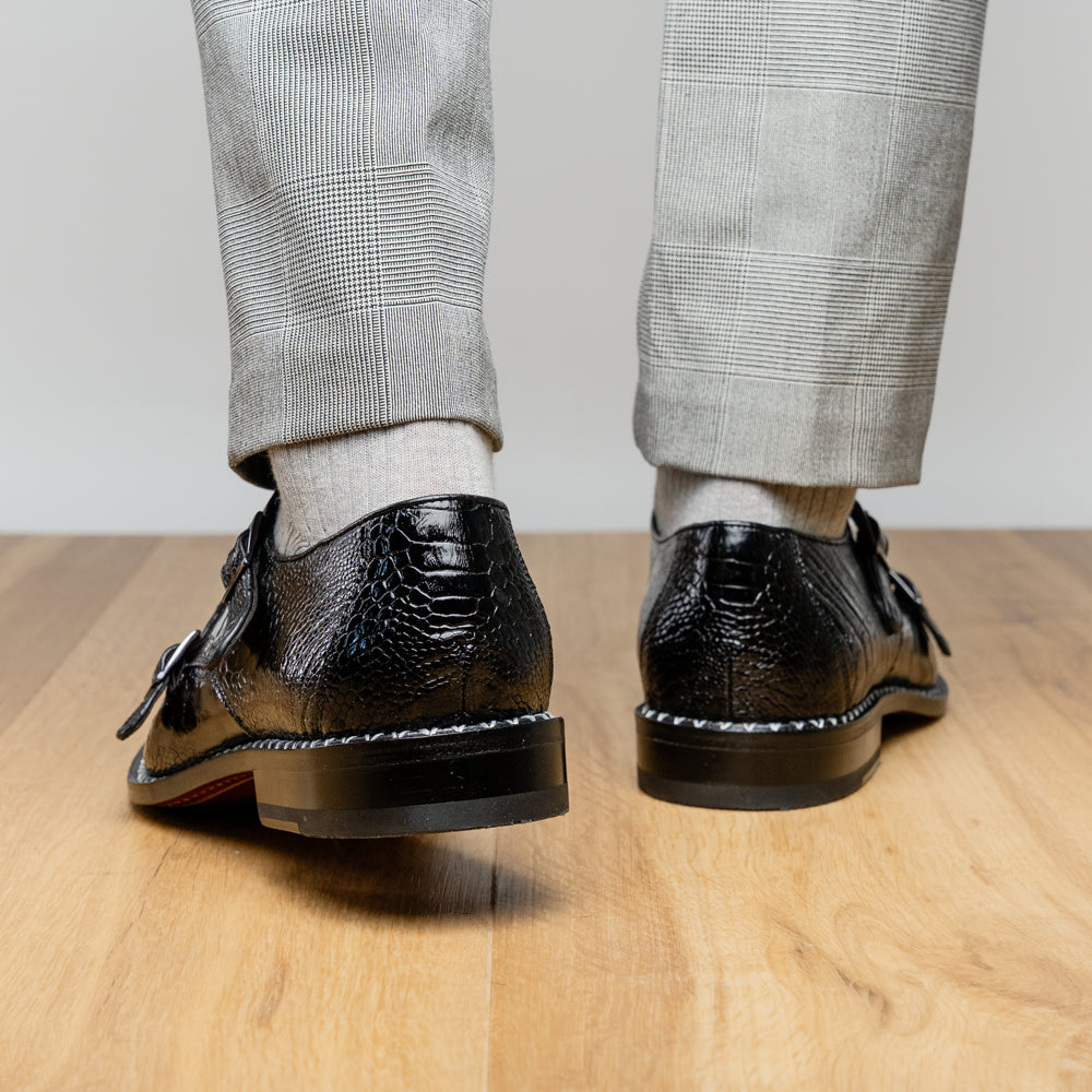 The Marco Di Milano Napoli Black is a pair of genuine ostrich leg dress shoes featuring a textured pattern, double monk strap, and brown branded sole—one shoe upright, the other showing the sole.