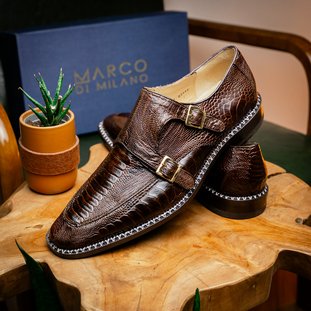 The Marco Di Milano Napoli Brown features brown leather double monk strap dress shoes with a genuine ostrich leg pattern and gold buckles, shown with one shoe upright and the other on its side.