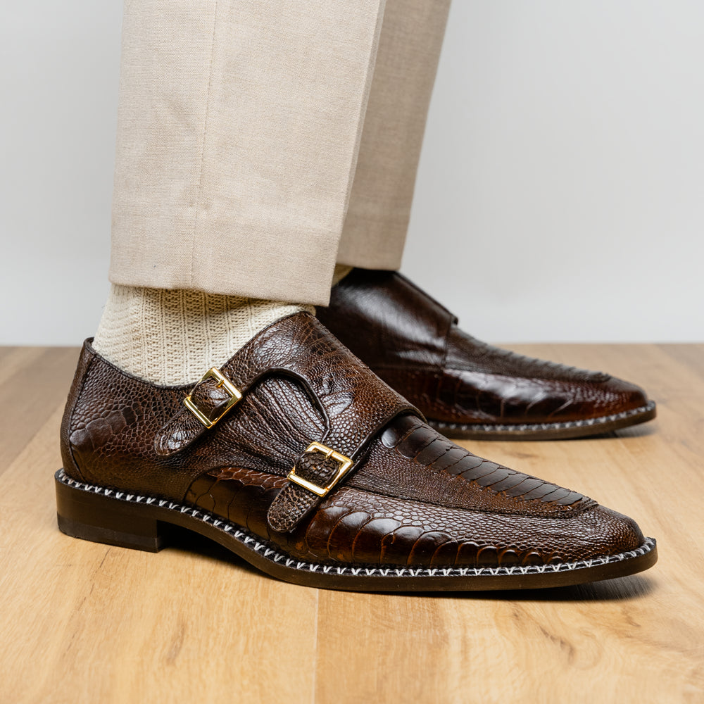 The Marco Di Milano Napoli Brown features brown leather double monk strap dress shoes with a genuine ostrich leg pattern and gold buckles, shown with one shoe upright and the other on its side.