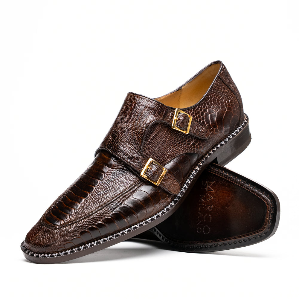 The Marco Di Milano Napoli Brown features brown leather double monk strap dress shoes with a genuine ostrich leg pattern and gold buckles, shown with one shoe upright and the other on its side.
