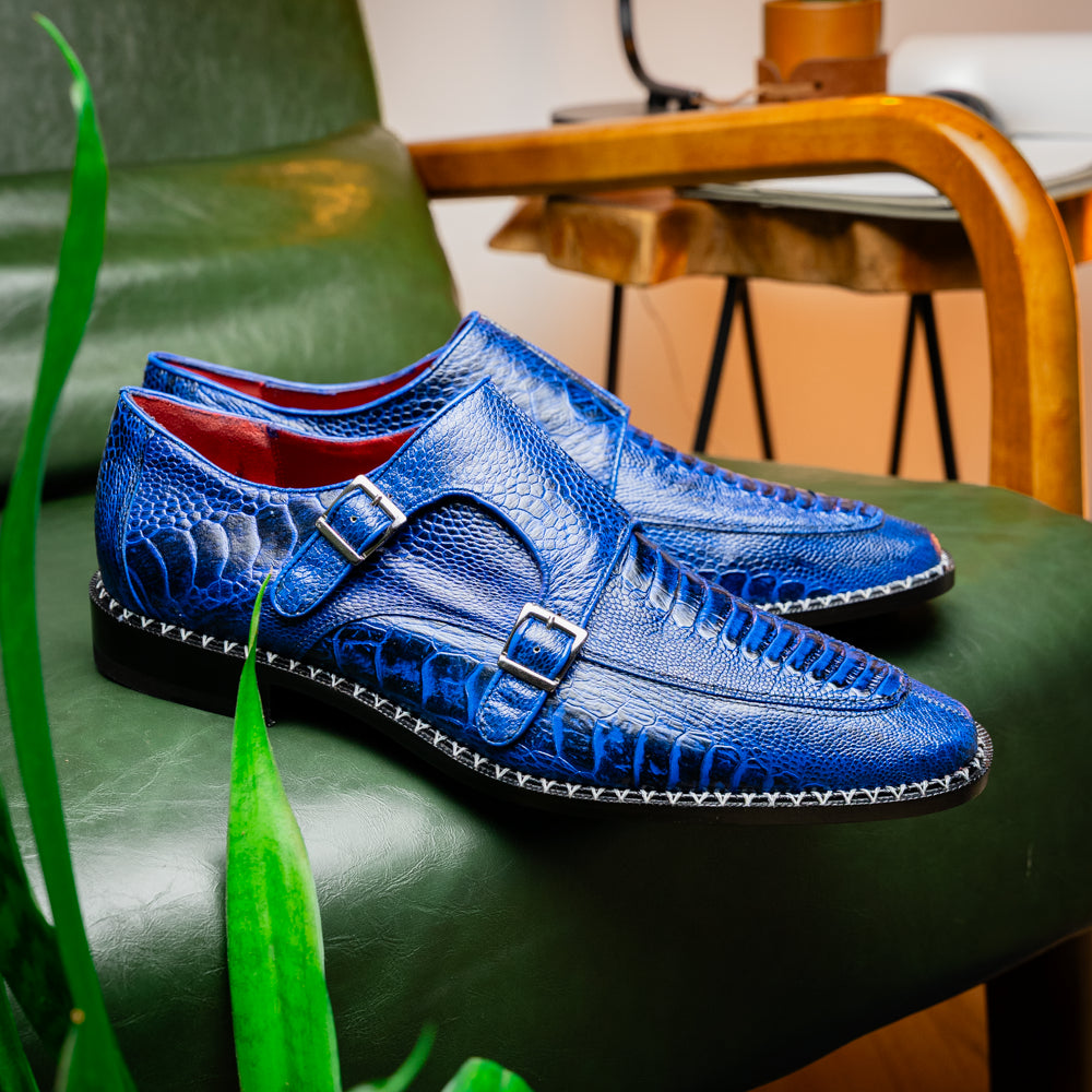 The Marco Di Milano Napoli Electric Blue exotic leather double monk strap shoes are shown: one upright and one on its side displaying the sole, set against a white background.