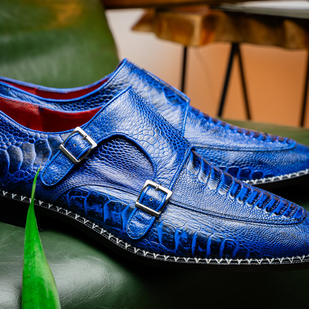 The Marco Di Milano Napoli Electric Blue exotic leather double monk strap shoes are shown: one upright and one on its side displaying the sole, set against a white background.