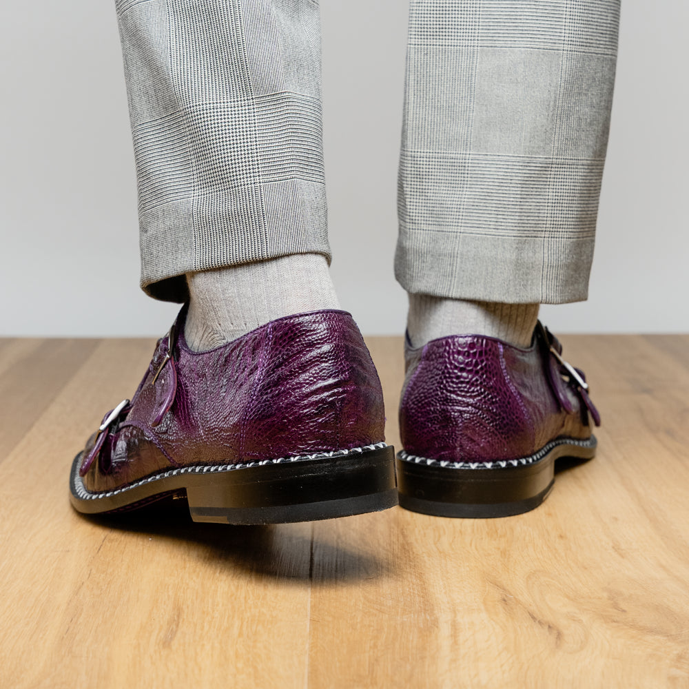 The Marco Di Milano Napoli Purple dress shoes feature genuine ostrich leather, a double monk strap, and textured detailing, with one shoe shown on its side to highlight the sole.