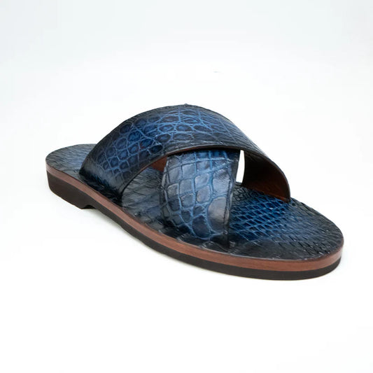 The Elios Navy by Marco Di Milano is a blue textured leather sandal with crisscross straps, a flat brown sole, and hand-painted finishes, shown on a white background.