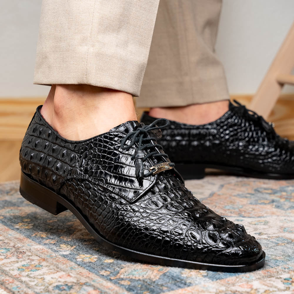 The Nilo Black by Marco Di Milano is a pair of luxury men's shoes made from polished black Nile crocodile skin with red inner lining and brown leather soles embossed with the brand name.