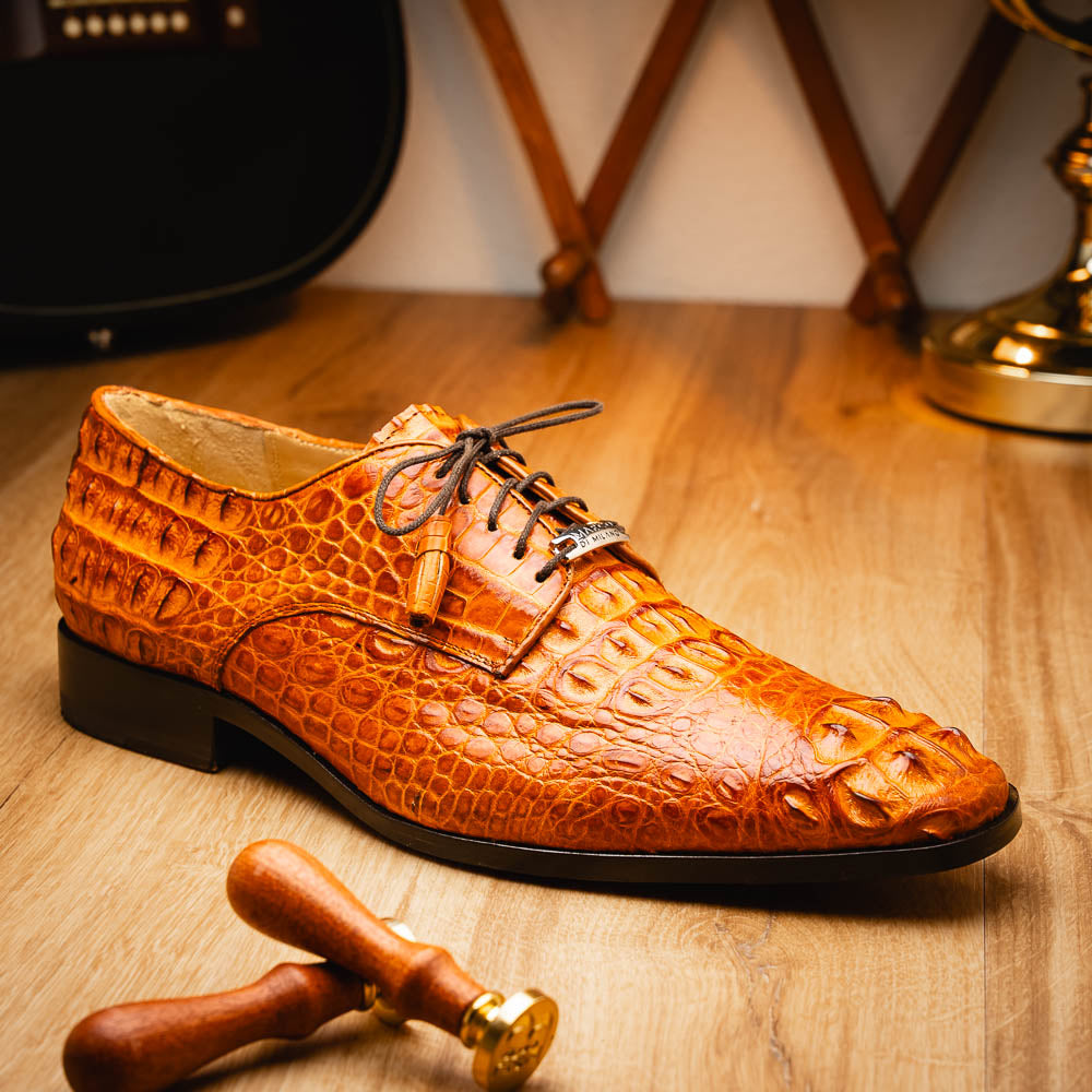 The Nilo Brandy by Marco Di Milano is a pair of orange luxury shoes made from Premium Nile Crocodile Skin with black laces—one shoe upright, the other flat to highlight its exquisite sole.