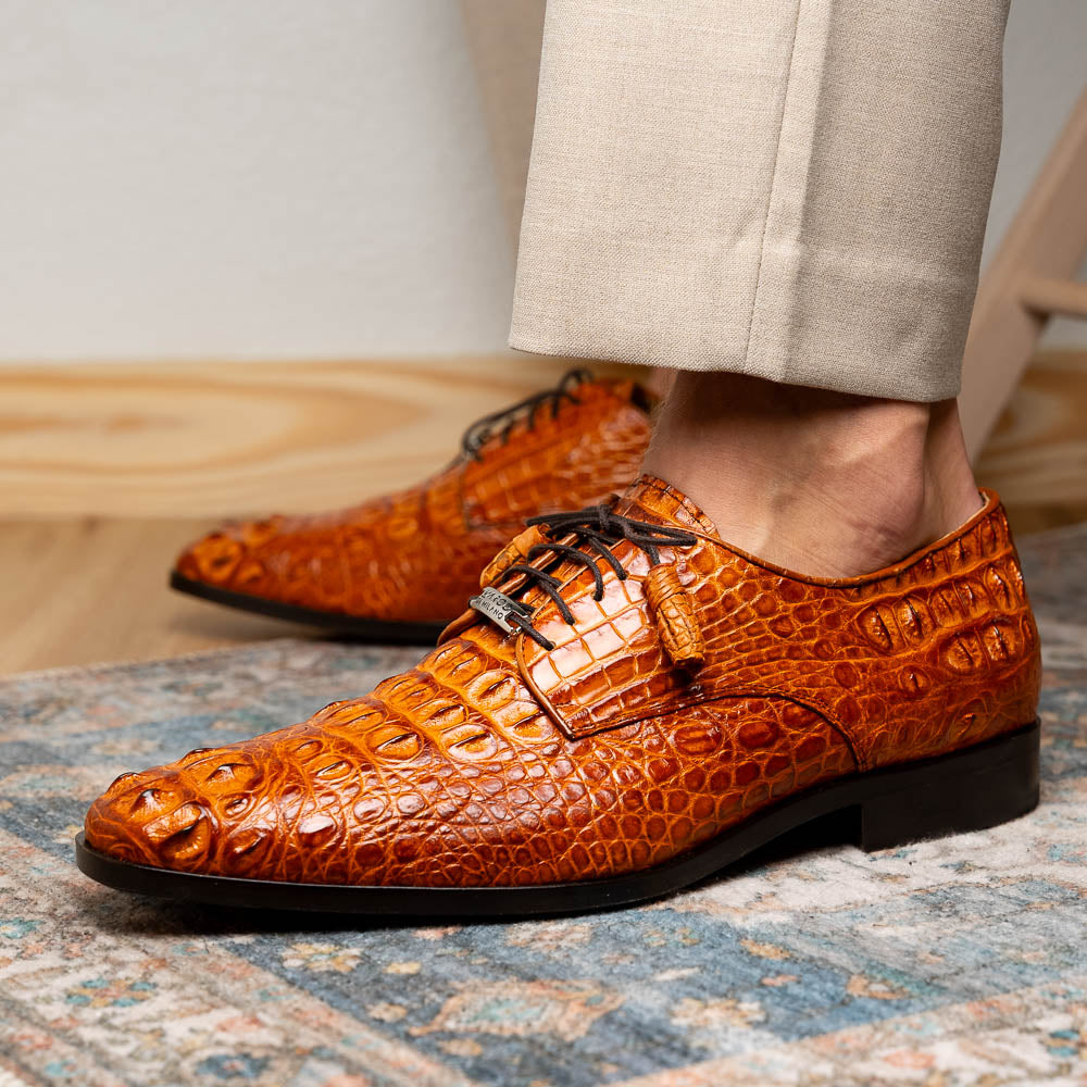 The Nilo Brandy by Marco Di Milano is a pair of orange luxury shoes made from Premium Nile Crocodile Skin with black laces—one shoe upright, the other flat to highlight its exquisite sole.