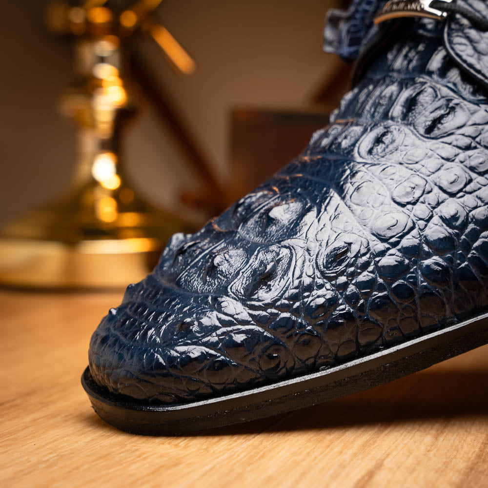 The Nilo Navy by Marco Di Milano features dark blue luxury footwear crafted from premium Nile crocodile skin with black laces and brown leather soles, displayed with one shoe propped on the other.