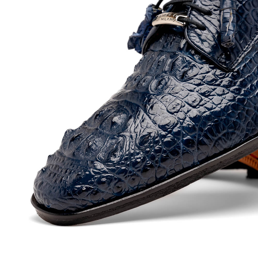 The Nilo Navy by Marco Di Milano features dark blue luxury footwear crafted from premium Nile crocodile skin with black laces and brown leather soles, displayed with one shoe propped on the other.