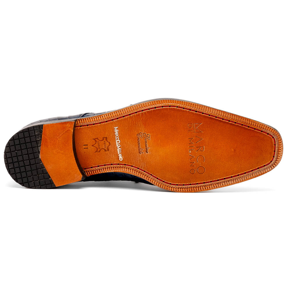 The Nilo Navy by Marco Di Milano features dark blue luxury footwear crafted from premium Nile crocodile skin with black laces and brown leather soles, displayed with one shoe propped on the other.