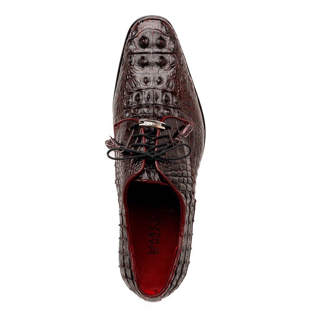 The Marco Di Milano Nilo Wine shoes are luxury dress footwear crafted from dark brown, textured Italian leather, featuring red interior lining and tan leather soles, with one shoe stylishly propped on the other.
