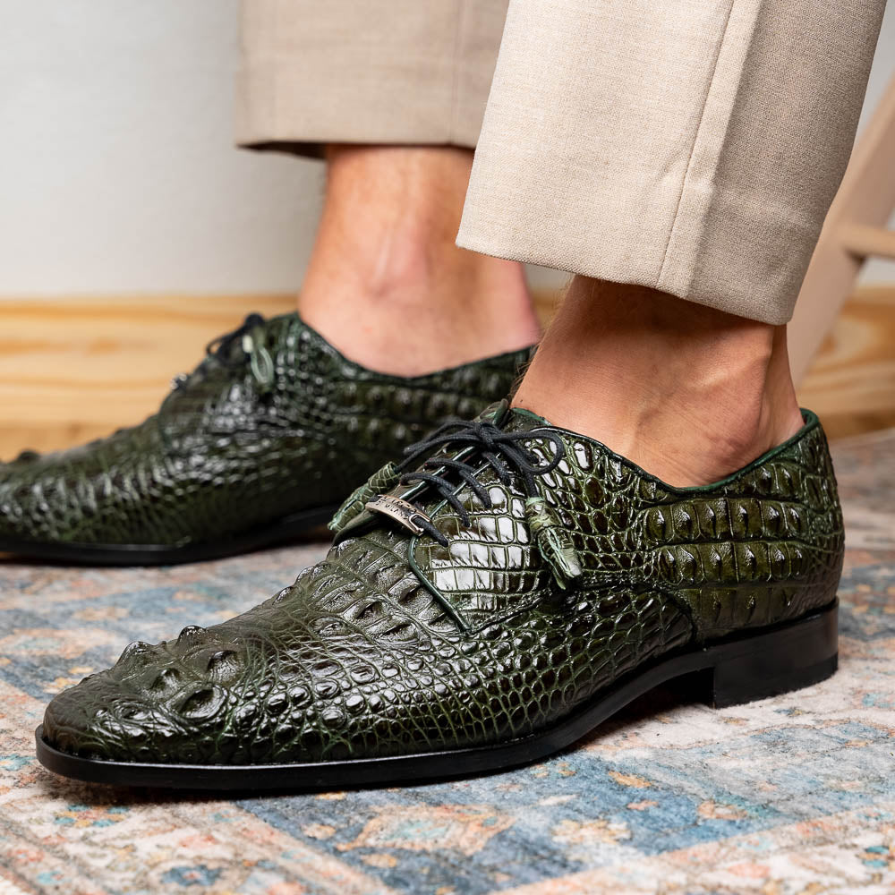 The Nilo Forest Green by Marco Di Milano is a luxury pair crafted from premium Nile crocodile skin in green, with black laces—one shoe upright, the other showing a branded brown leather sole.
