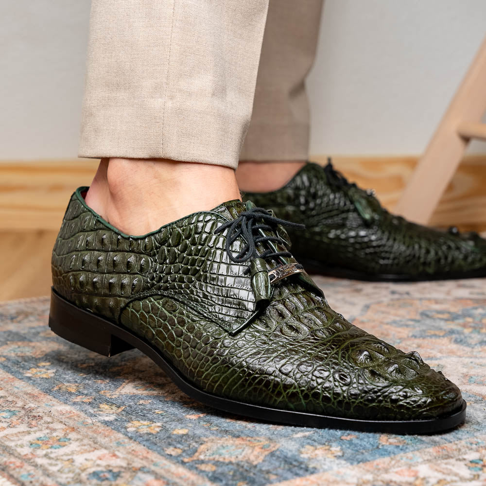 The Nilo Forest Green by Marco Di Milano is a luxury pair crafted from premium Nile crocodile skin in green, with black laces—one shoe upright, the other showing a branded brown leather sole.