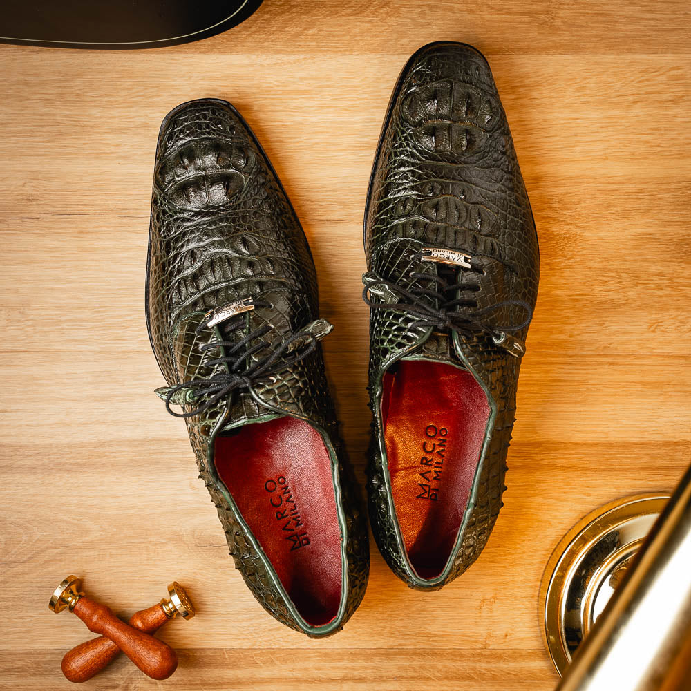 The Nilo Forest Green by Marco Di Milano is a luxury pair crafted from premium Nile crocodile skin in green, with black laces—one shoe upright, the other showing a branded brown leather sole.