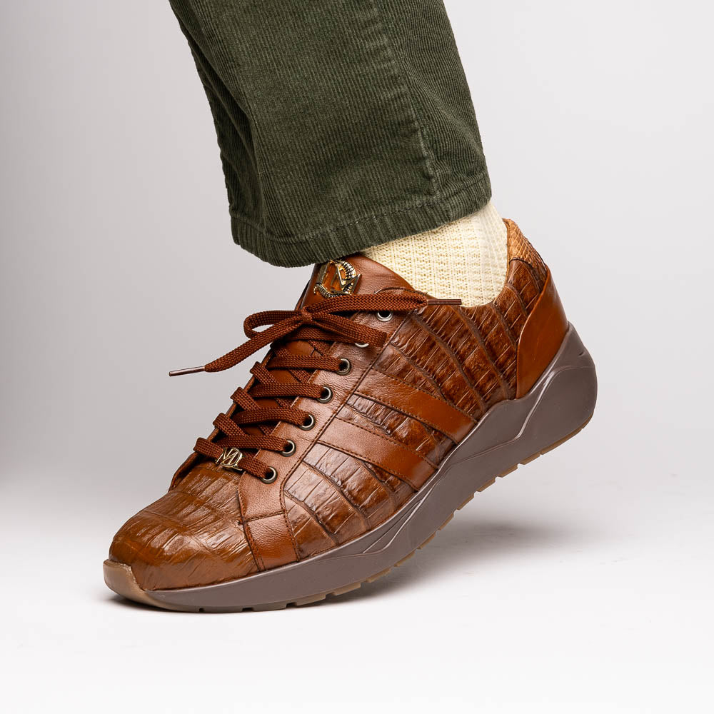 The Marco Di Milano Nino Bay Apache: luxurious brown genuine caiman crocodile sneakers, hand-painted with dark brown laces and grooved rubber soles—one stands upright while the other is shown lying on its side.