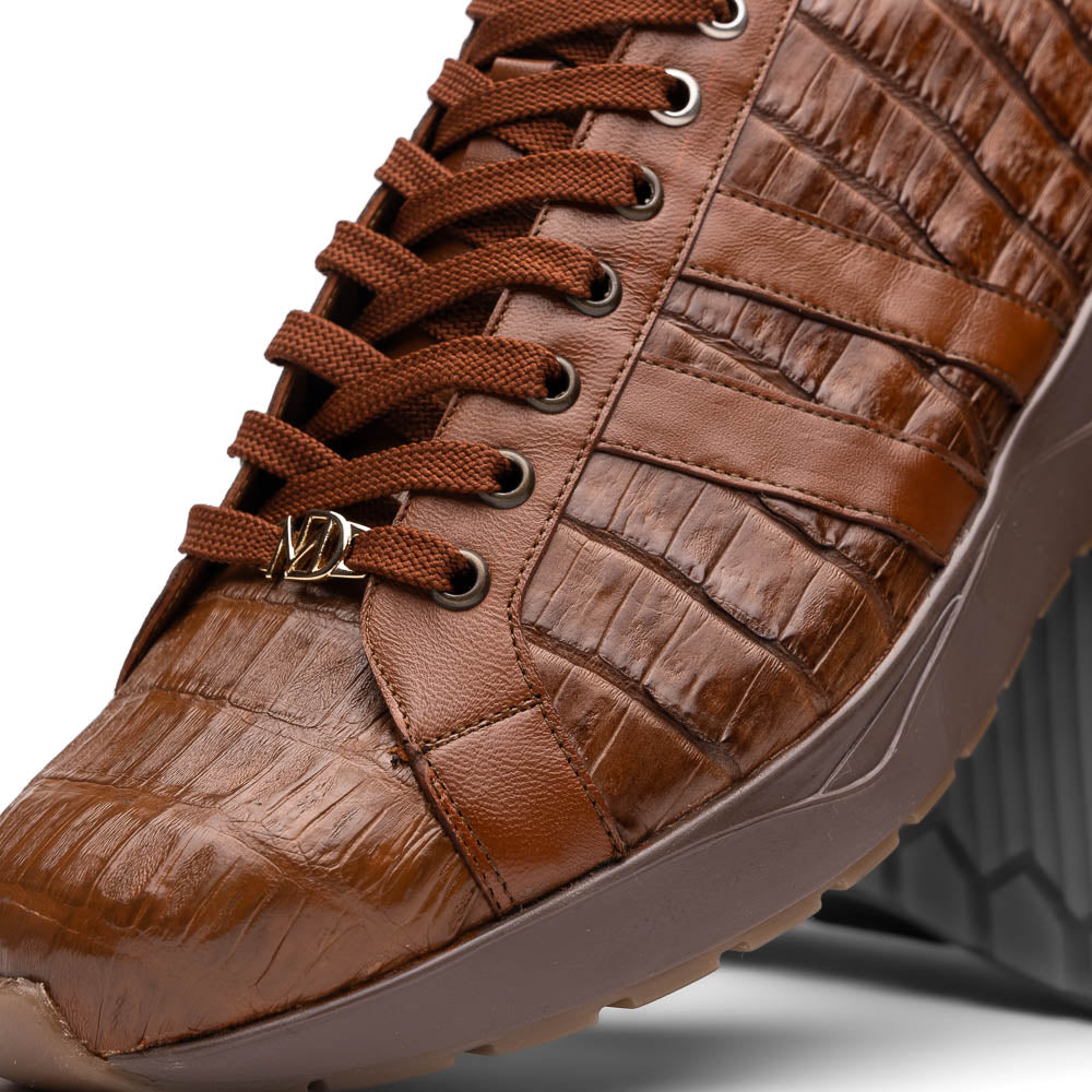 The Marco Di Milano Nino Bay Apache: luxurious brown genuine caiman crocodile sneakers, hand-painted with dark brown laces and grooved rubber soles—one stands upright while the other is shown lying on its side.