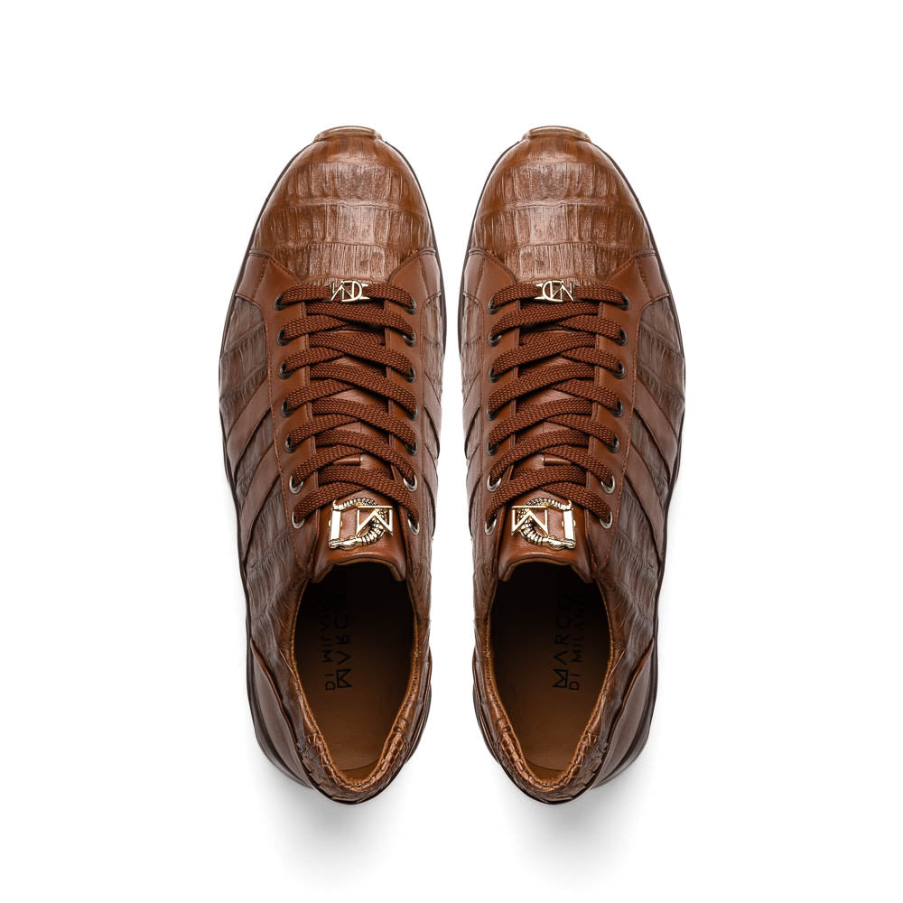 The Marco Di Milano Nino Bay Apache: luxurious brown genuine caiman crocodile sneakers, hand-painted with dark brown laces and grooved rubber soles—one stands upright while the other is shown lying on its side.