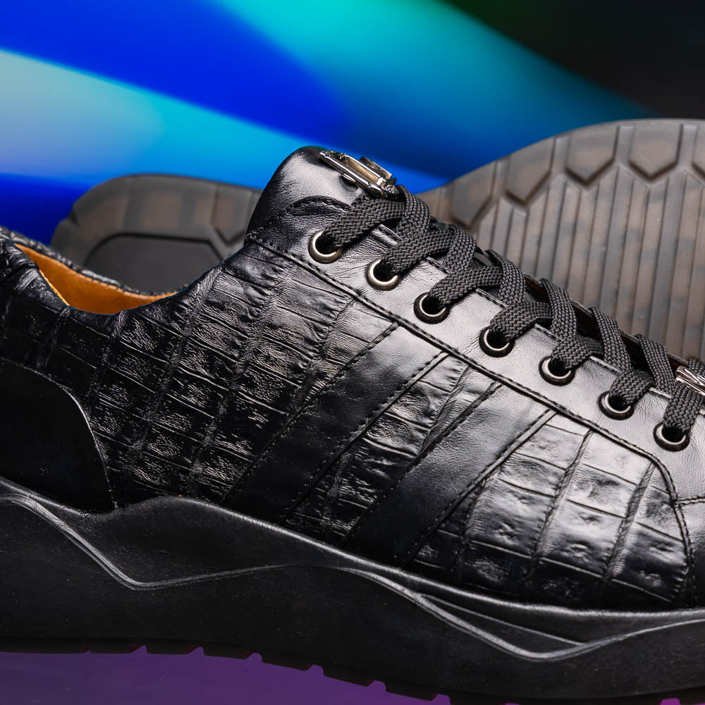 The Nino Black by Marco Di Milano: genuine black caiman crocodile sneakers with black laces and a textured rubber sole, one standing and one leaning, highlighting luxury footwear with a striking hand painted finish.