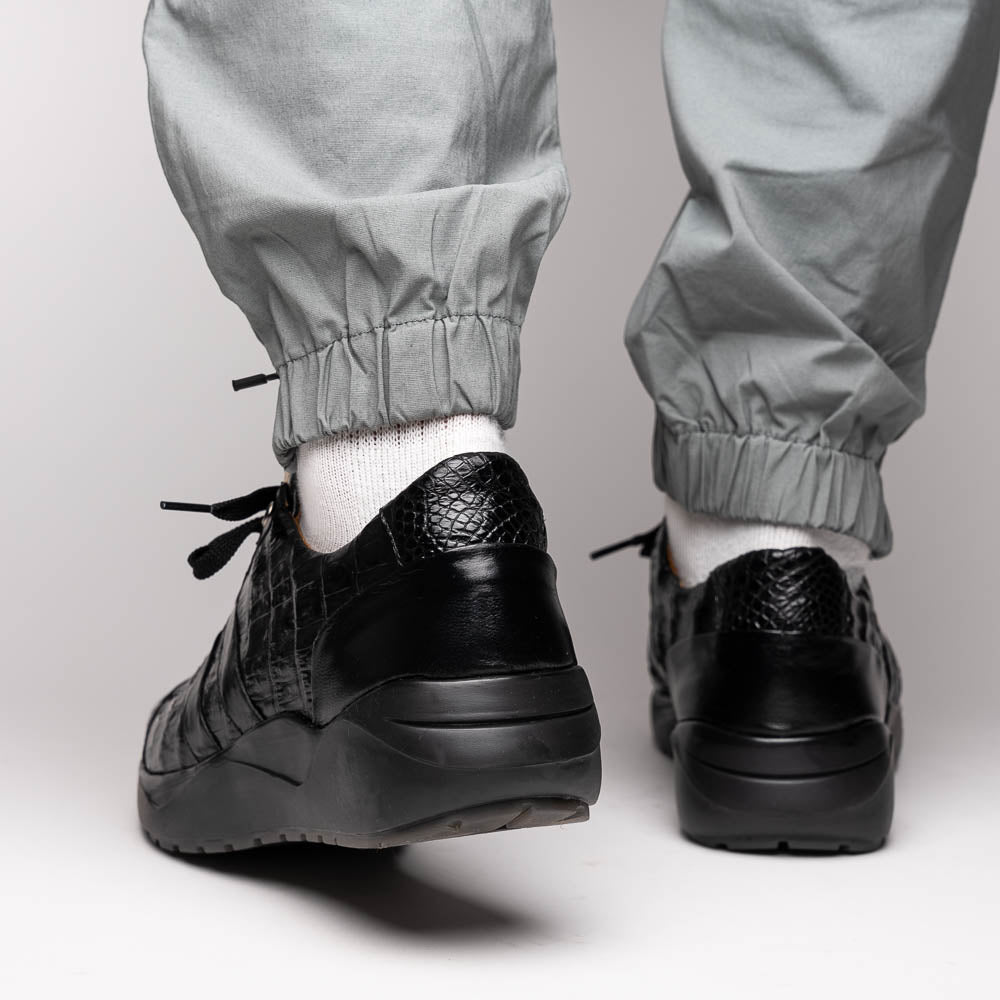 The Nino Black by Marco Di Milano: genuine black caiman crocodile sneakers with black laces and a textured rubber sole, one standing and one leaning, highlighting luxury footwear with a striking hand painted finish.
