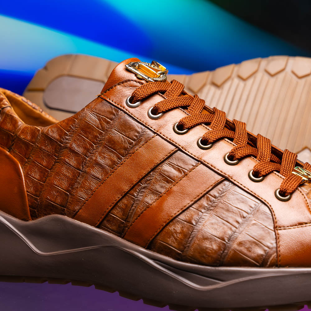 The Marco Di Milano Nino Bay Apache: luxurious brown genuine caiman crocodile sneakers, hand-painted with dark brown laces and grooved rubber soles—one stands upright while the other is shown lying on its side.