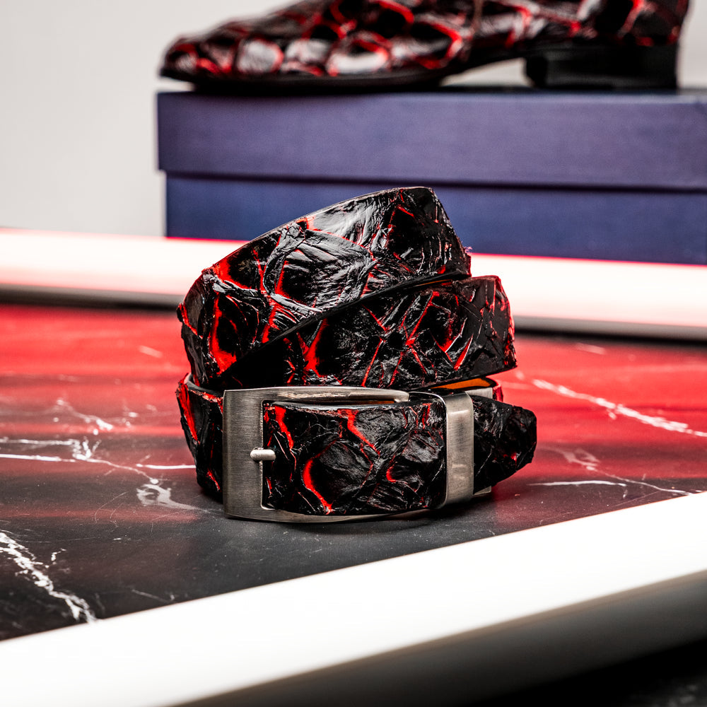 The Olivieri Belt Blackcherry by Marco Di Milano is a luxury men’s accessory crafted from black leather with red textured patterns, rolled up and showcased with a silver rectangular buckle on a white background—making it an exquisite exotic leather belt choice for any sophisticated wardrobe.