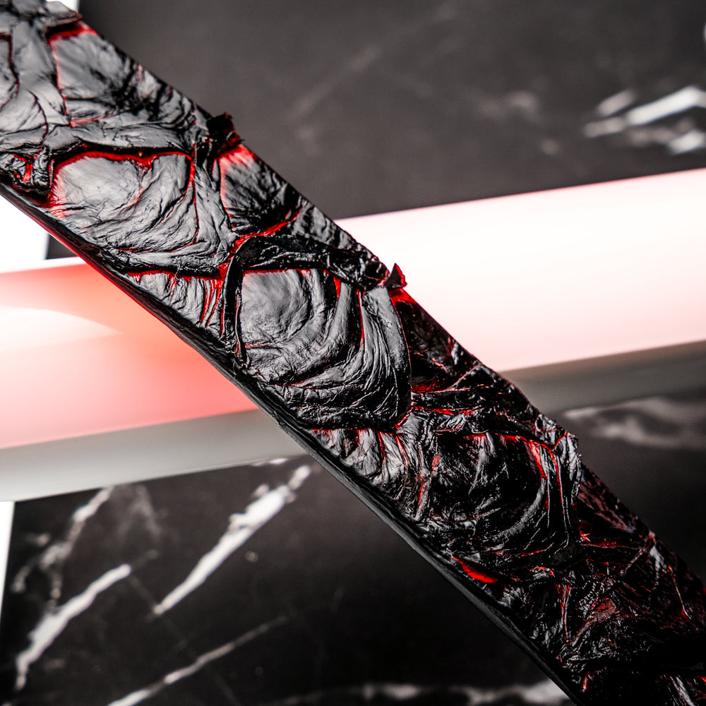 The Olivieri Belt Blackcherry by Marco Di Milano is a luxury men’s accessory crafted from black leather with red textured patterns, rolled up and showcased with a silver rectangular buckle on a white background—making it an exquisite exotic leather belt choice for any sophisticated wardrobe.