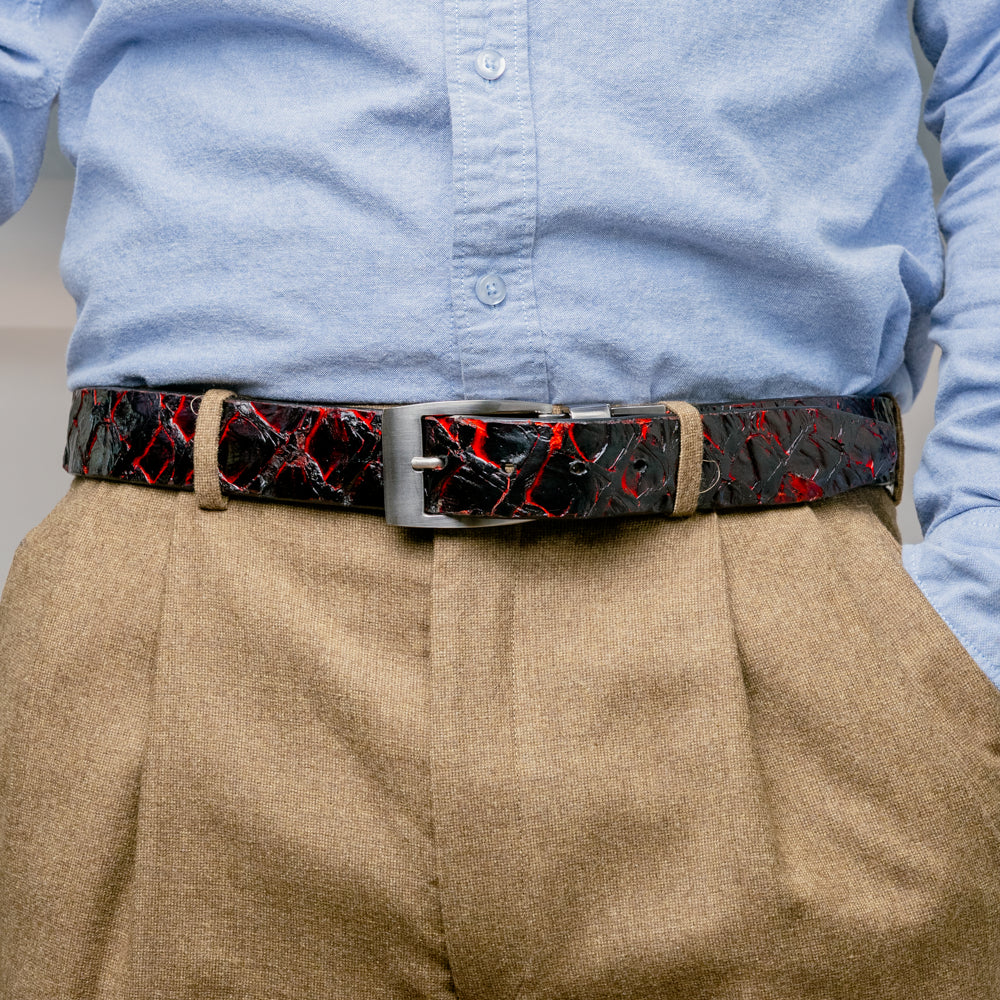 The Olivieri Belt Blackcherry by Marco Di Milano is a luxury men’s accessory crafted from black leather with red textured patterns, rolled up and showcased with a silver rectangular buckle on a white background—making it an exquisite exotic leather belt choice for any sophisticated wardrobe.