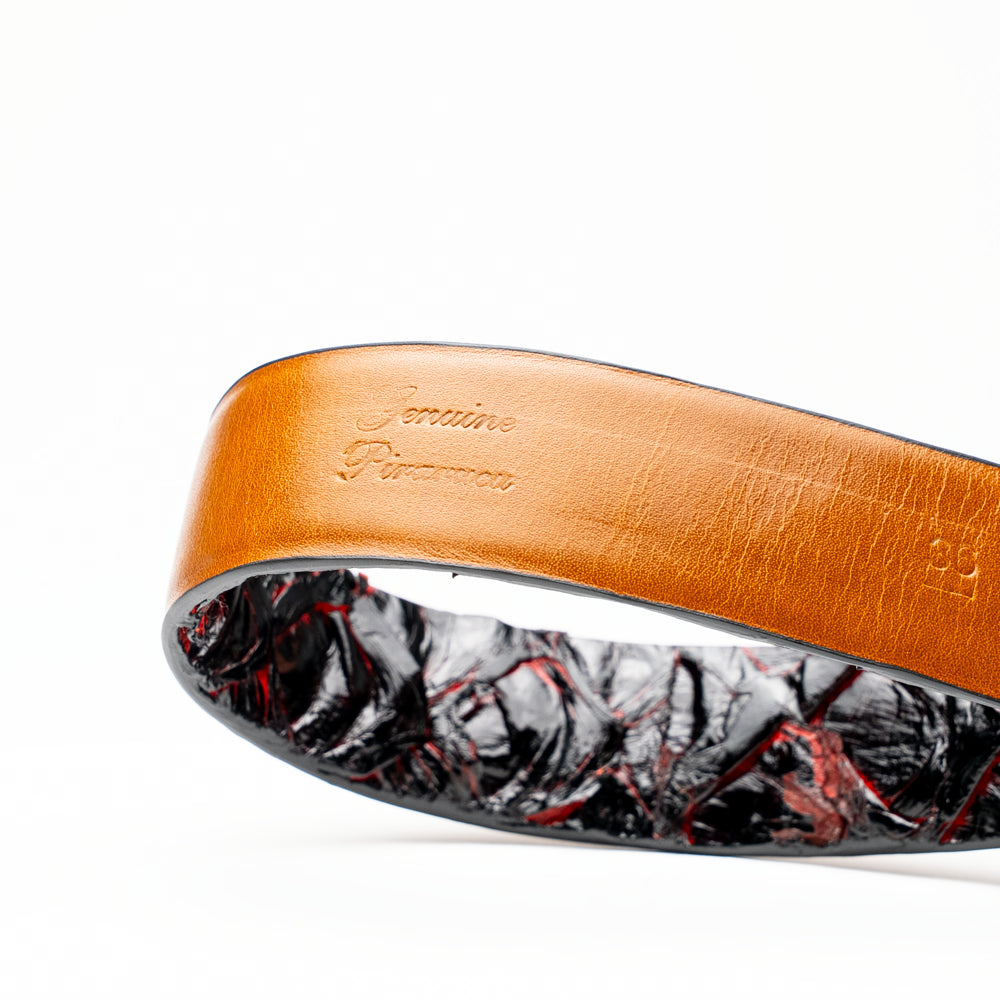 The Olivieri Belt Blackcherry by Marco Di Milano is a luxury men’s accessory crafted from black leather with red textured patterns, rolled up and showcased with a silver rectangular buckle on a white background—making it an exquisite exotic leather belt choice for any sophisticated wardrobe.