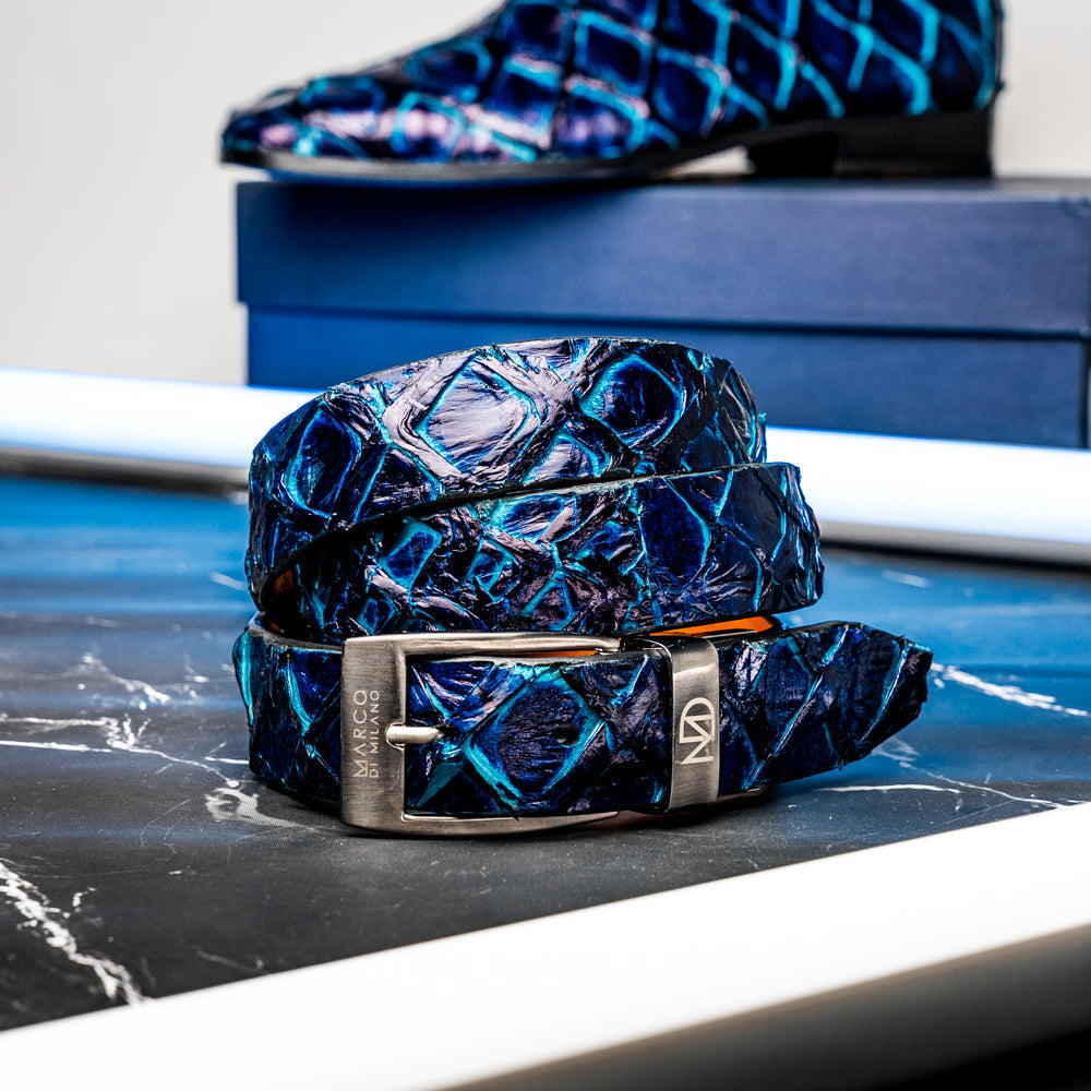 The Olivieri Belt Royal Blue by Marco Di Milano, featuring blue textured genuine pirarucu leather and a silver buckle, is coiled elegantly against a white background—an exquisite example of an exotic belt designed for the discerning gentleman.