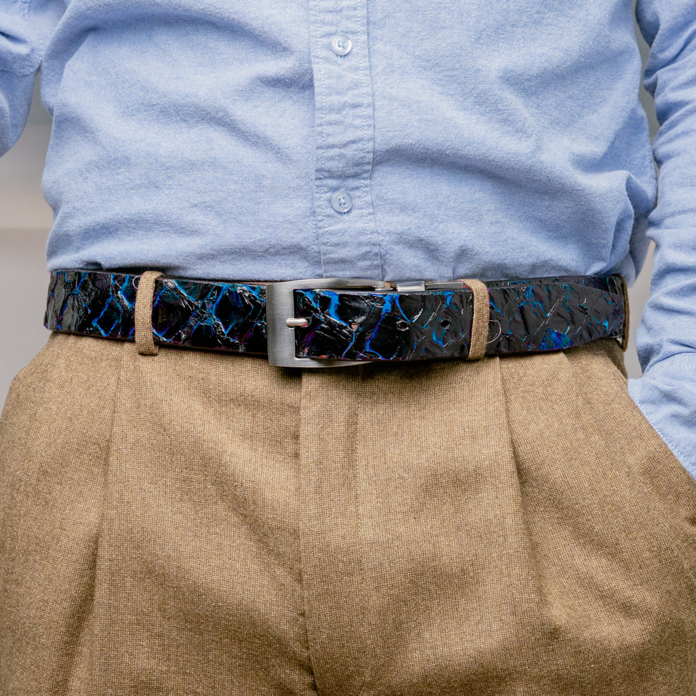 The Olivieri Belt Royal Blue by Marco Di Milano, featuring blue textured genuine pirarucu leather and a silver buckle, is coiled elegantly against a white background—an exquisite example of an exotic belt designed for the discerning gentleman.