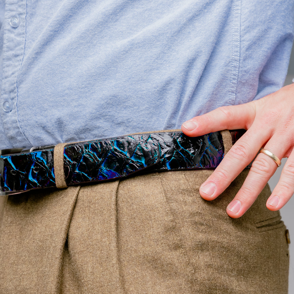 The Olivieri Belt Royal Blue by Marco Di Milano, featuring blue textured genuine pirarucu leather and a silver buckle, is coiled elegantly against a white background—an exquisite example of an exotic belt designed for the discerning gentleman.