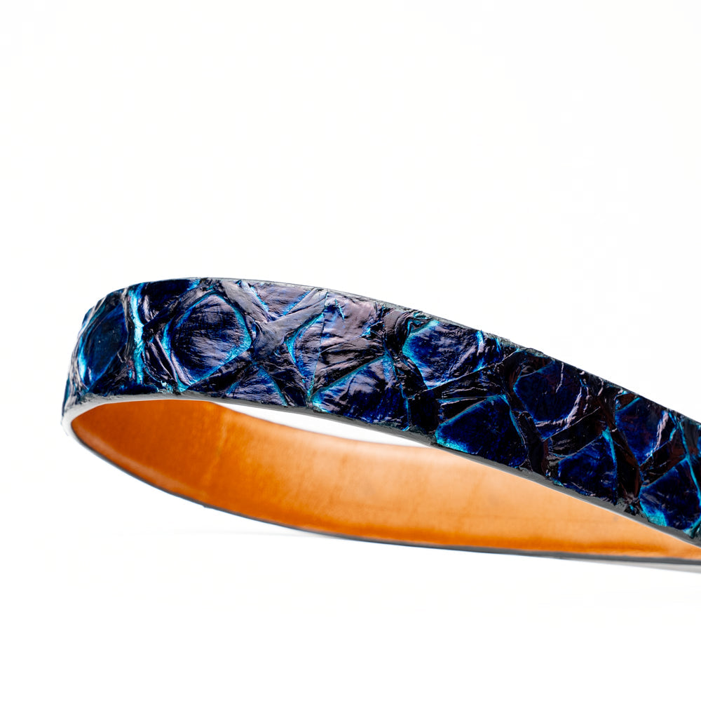 The Olivieri Belt Royal Blue by Marco Di Milano, featuring blue textured genuine pirarucu leather and a silver buckle, is coiled elegantly against a white background—an exquisite example of an exotic belt designed for the discerning gentleman.