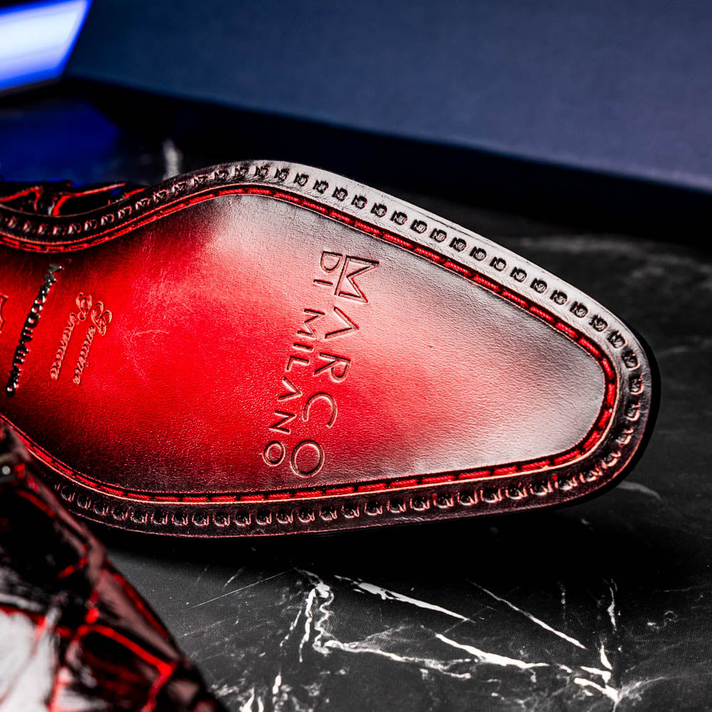 A pair of Marco Di Milano Olivieri Blackcherry oxfords—one upright, one on its side—displays the brand name on the sole, offering luxury men’s footwear with a strikingly exotic black and red pirarucu finish.