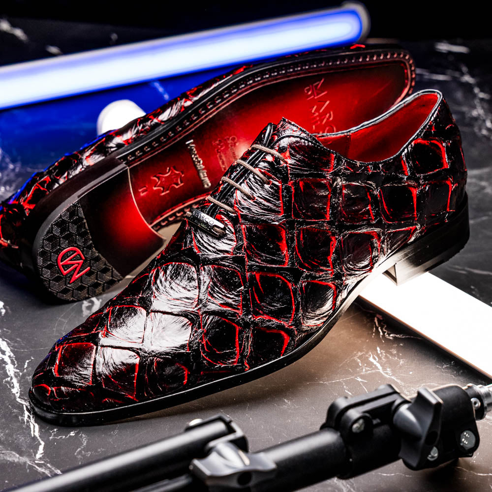 A pair of Marco Di Milano Olivieri Blackcherry oxfords—one upright, one on its side—displays the brand name on the sole, offering luxury men’s footwear with a strikingly exotic black and red pirarucu finish.