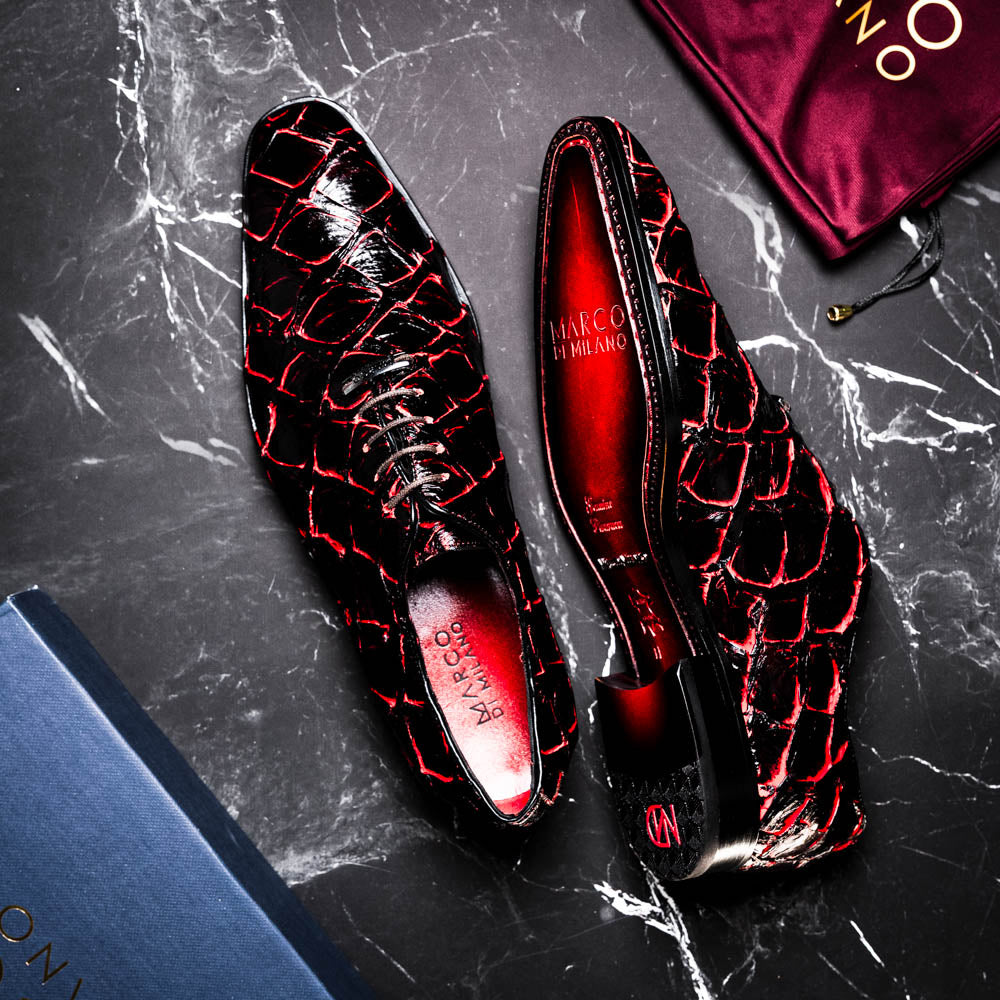 A pair of Marco Di Milano Olivieri Blackcherry oxfords—one upright, one on its side—displays the brand name on the sole, offering luxury men’s footwear with a strikingly exotic black and red pirarucu finish.