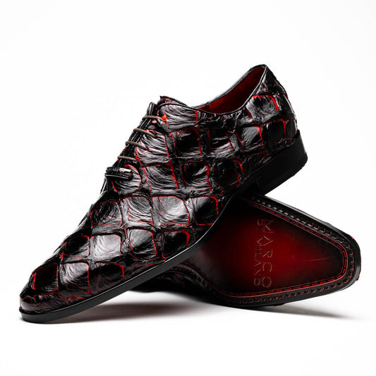 A pair of Marco Di Milano Olivieri Blackcherry oxfords—one upright, one on its side—displays the brand name on the sole, offering luxury men’s footwear with a strikingly exotic black and red pirarucu finish.