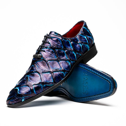 The Olivieri Royal Blue by Marco Di Milano is a pair of men's dress shoes featuring a blue and black textured design. One shoe stands upright, the other displays a bright blue sole with "Marco Di Milano" branding—true luxury.