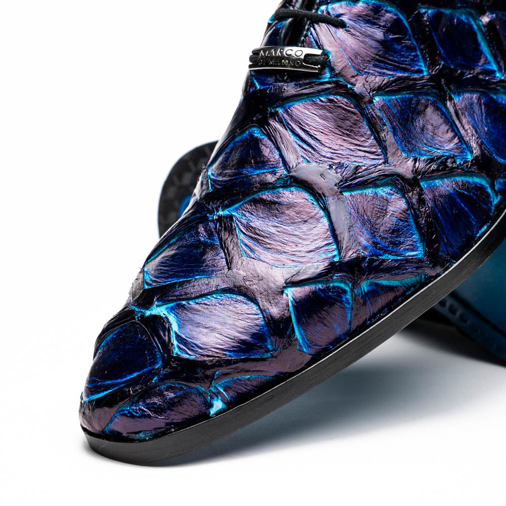 The Olivieri Royal Blue by Marco Di Milano is a pair of men's dress shoes featuring a blue and black textured design. One shoe stands upright, the other displays a bright blue sole with "Marco Di Milano" branding—true luxury.